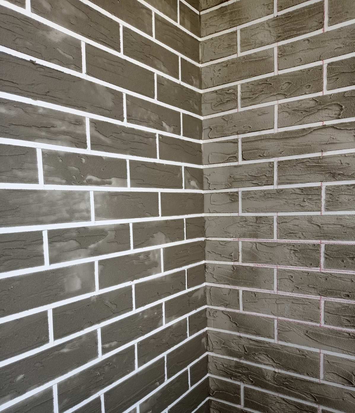 Šviesių plytelių mūro sienos detalė